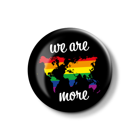 **Alt-Text**: Bunte Anstecknadel mit einer Weltkarte in Regenbogenfarben und dem Schriftzug "we are more".
